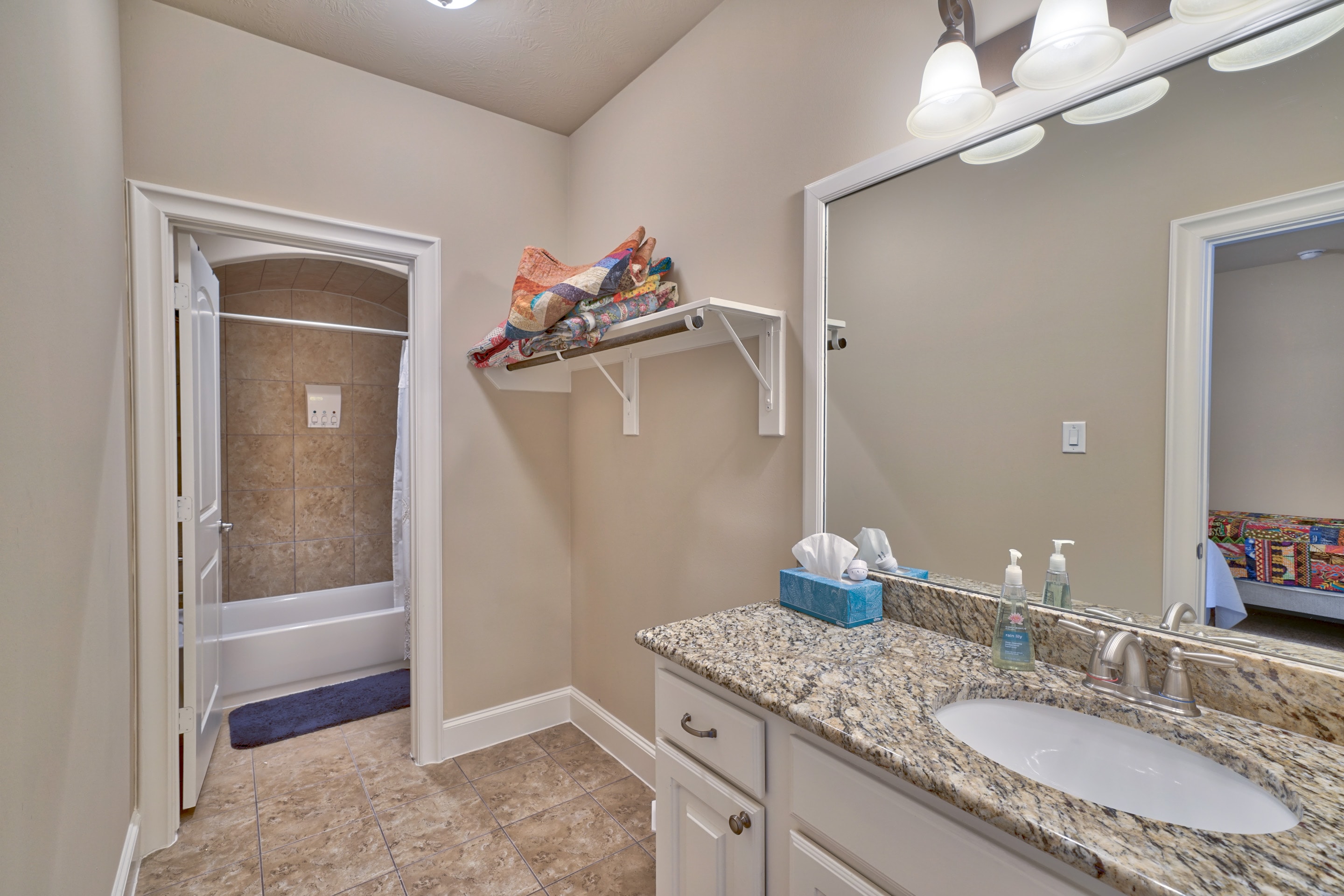 Private bathroom with granite countertop, vanity mirror, and shower