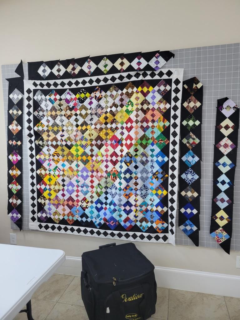 Colorful diamond-patterned quilt in progress displayed on the design wall in the workroom